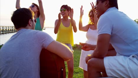 gente multiétnica con guitarra bailando en la playa