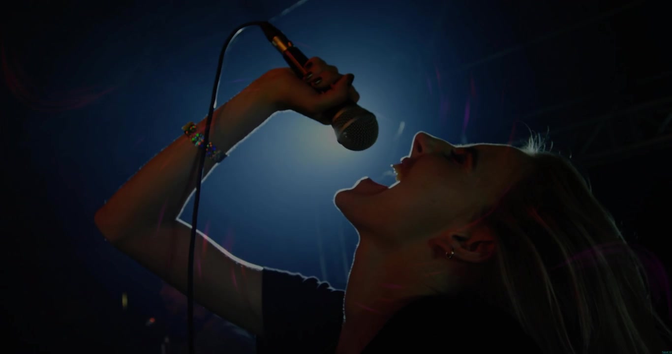 Woman singer stepping forward and raising microphone causing magenta swirls while leading concert