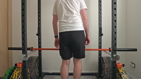 static shot of a man unracking the barbell and placing it on the safety pins