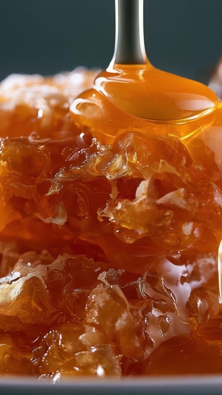 Un primer plano de miel dorada goteando de una cuchara, mostrando la rica textura y el dulce aroma del panal natural para los entusiastas culinarios.
