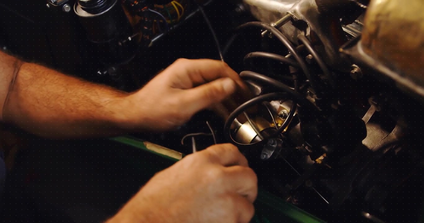 Mechanic detaching spark plug connector with scan overlay, routing harness neatly in auto bay