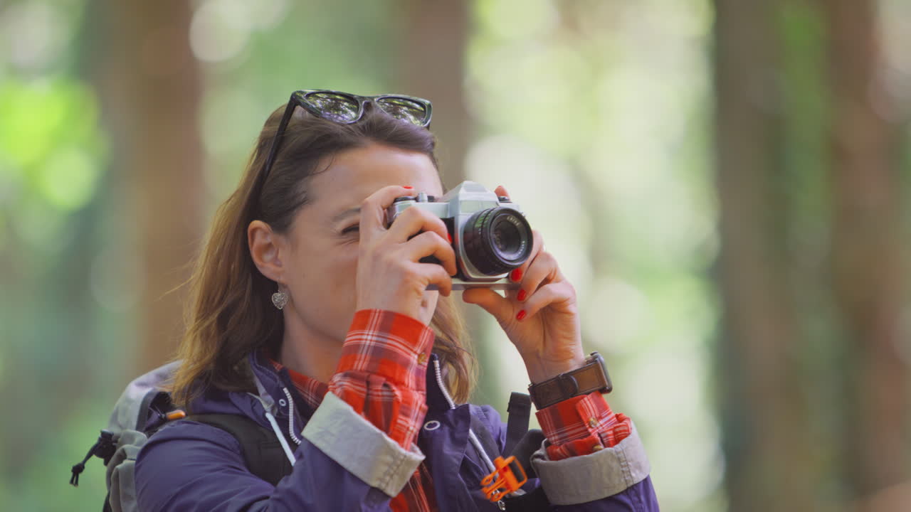 mujer en una caminata por el bosque tomando fotos con una cámara dslr