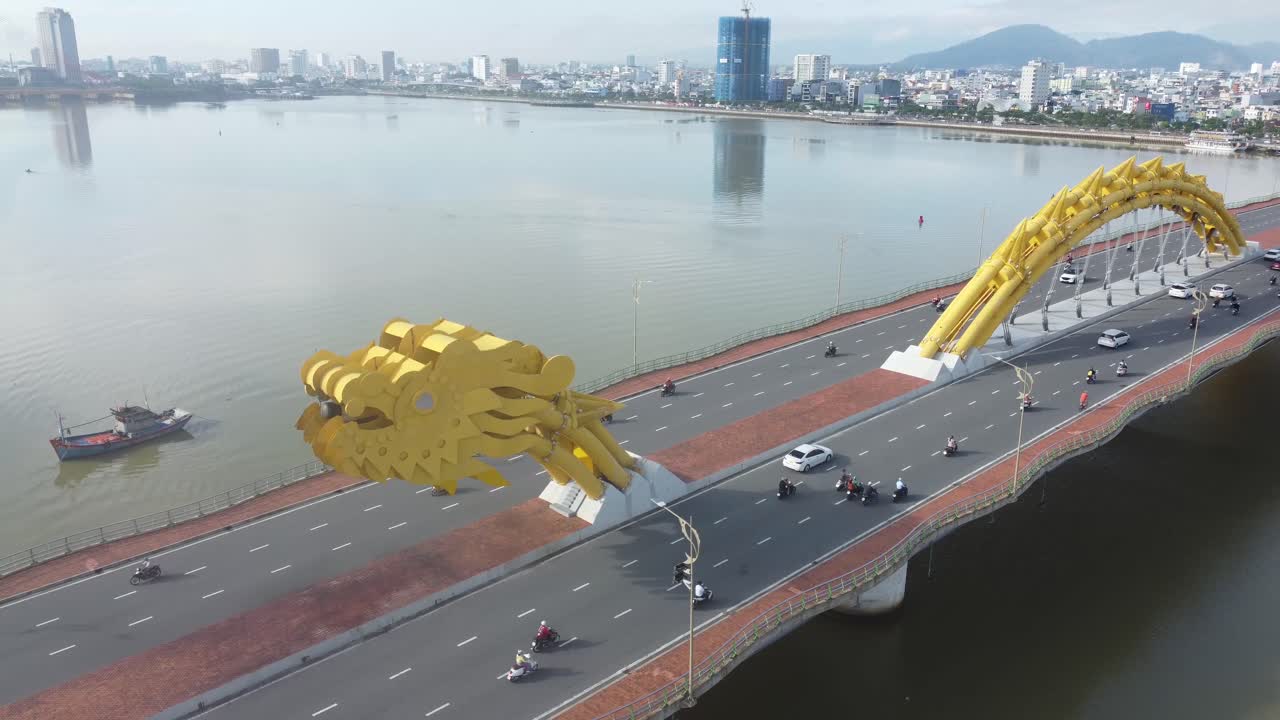 Cảnh quay flycam cầu Rồng trên sông Hàn ở Đà Nẵng, Việt Nam, với vòm cầu hình rồng vàng và khung cảnh đô thị của thành phố.