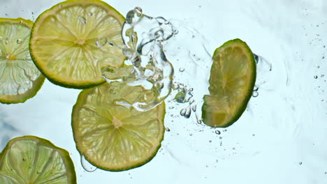 fresh lime slices falling water close up. juicy pieces acidic citrus floating.