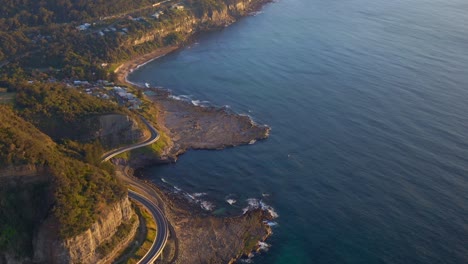 Vista-Aérea-De-La-Carretera-Sinuosa-En-El-Puente-Del-Acantilado-Del-Mar-Al-Amanecer-En-Clifton,-Australia