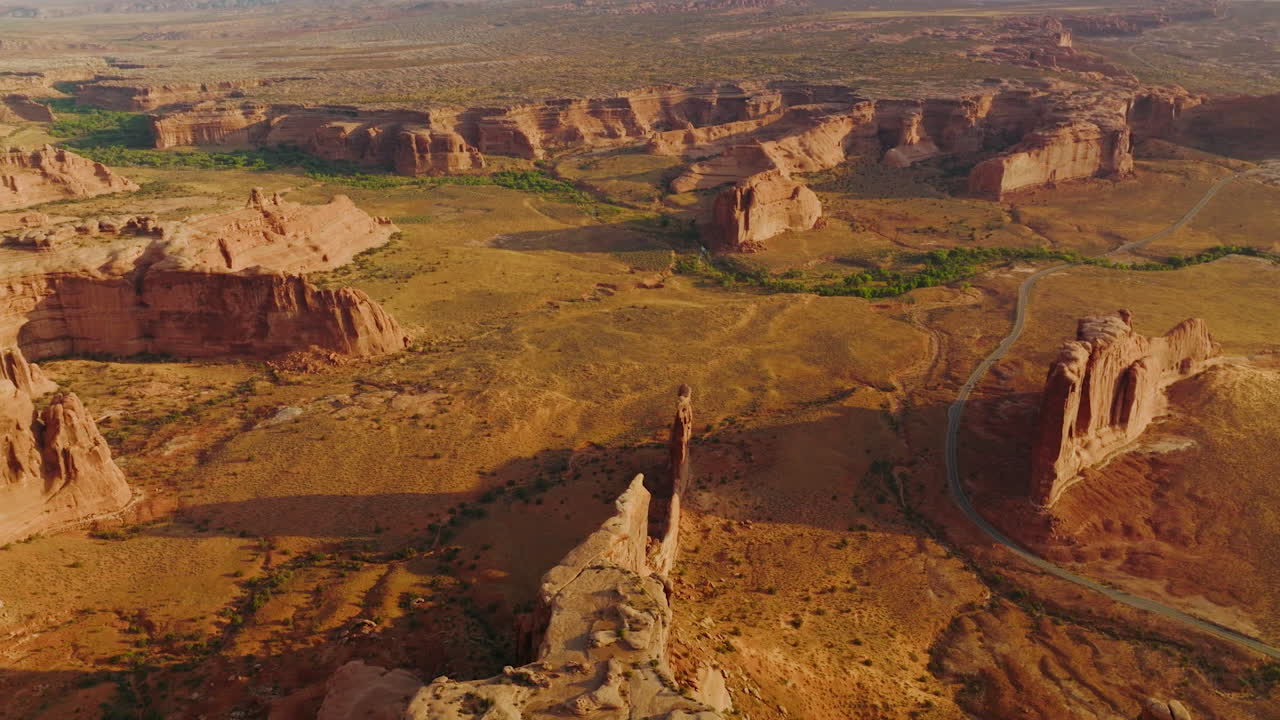 Deserted dry land with big stunning rocks of canyons. Sunlit panorama of Arches National Park from aerial perspective.