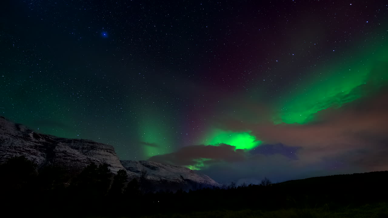 Scenic northern lights in the Norwegian Arctic over snowy mountain, timelapse