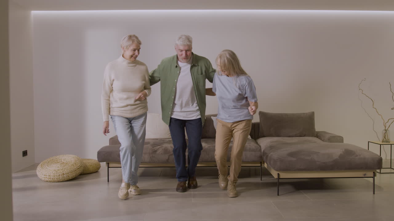 Tre anziani amici felici che ballano insieme a casa 2