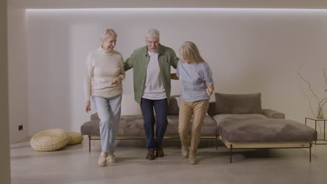 three happy senior friends dancing together at home 2