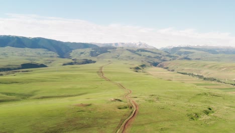 mountain peaks and grassland are under white clouds.