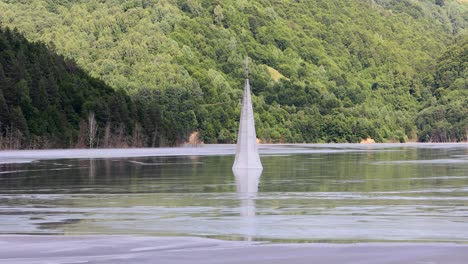 spire of the church above the flooded village of geamana by toxic lake in lupsa, romania