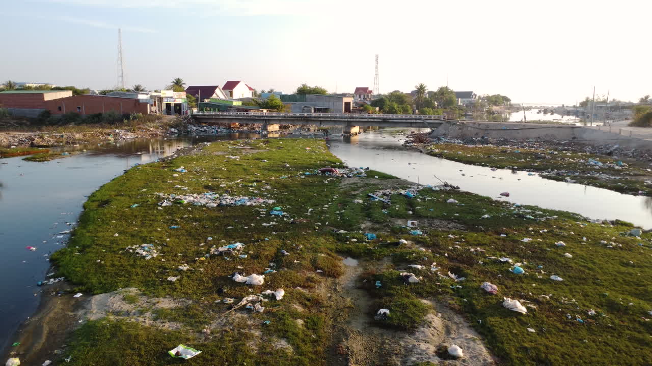 Scene with garbage on bank of polluted river, Vietnam