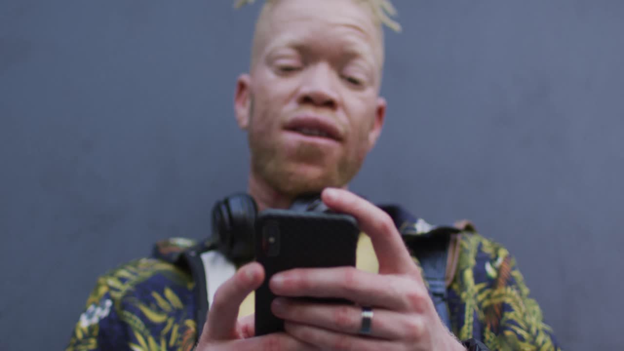 hombre albino afroamericano pensativo con rastas usando un teléfono inteligente