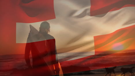 animation of flag of switzerland over caucasian male surfer at beach
