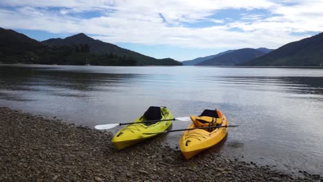 cámara lenta: dos kayaks en una playa rocosa junto al lago.