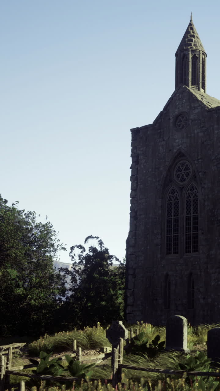 Smuk gammel kirke står nær en fredfyldt kirkegård i skarpt sollys.