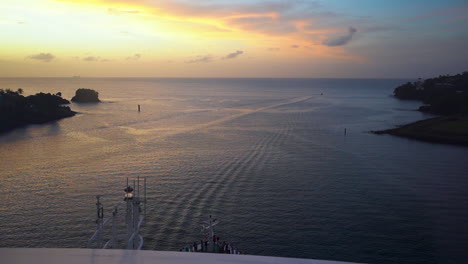 vista de lapso de tiempo desde un crucero que navega desde un puerto en el mar caribe, en dirección al océano abierto hacia una puesta de sol dorada en el horizonte, evitando acantilados y arrecifes, lapso de tiempo fhd
