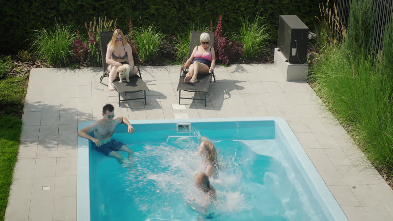 Mor og datter hopper i poolen, glad familie hygger sig