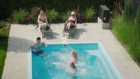 Mom-and-daughter-jump-into-the-pool,-friendly-family-having-a-good-time