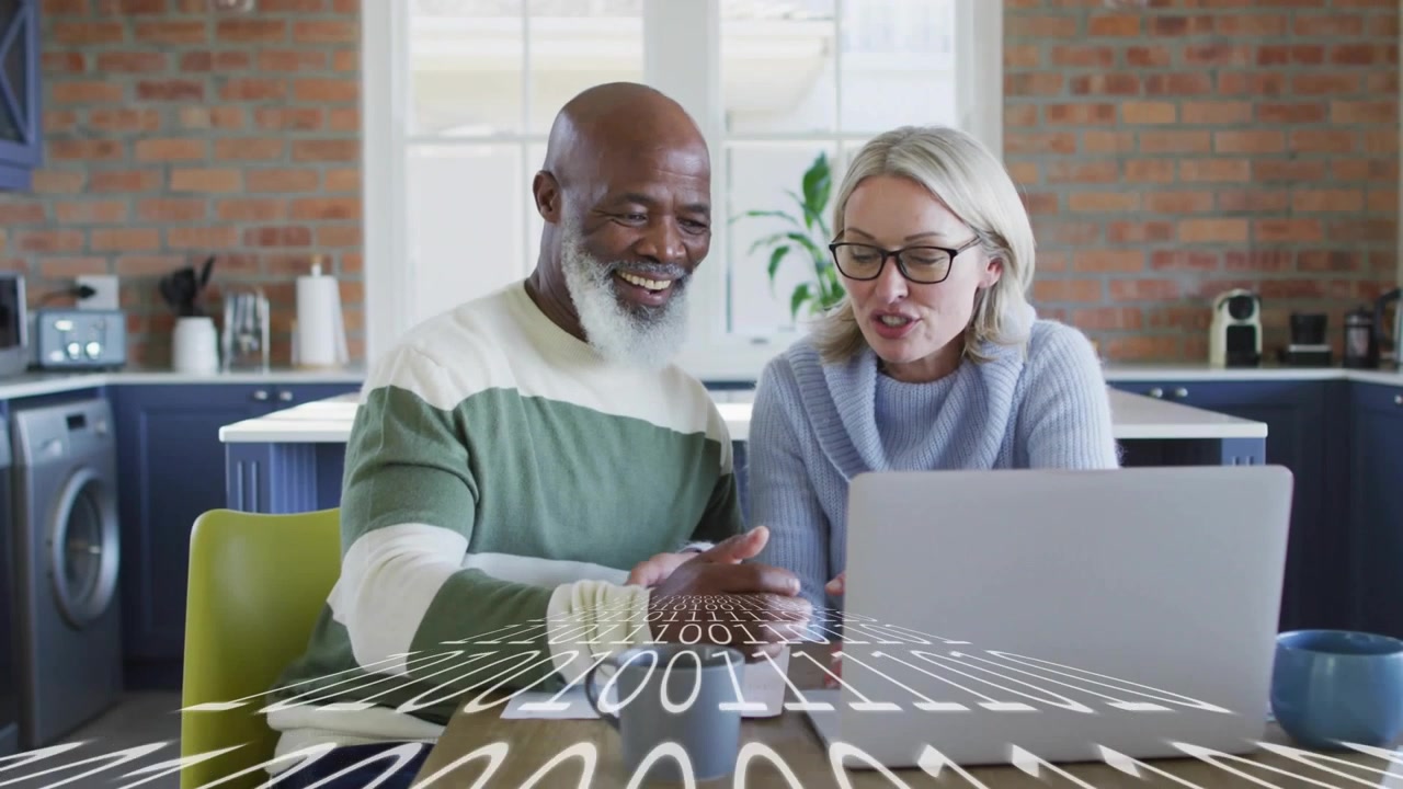 Couple sitting at kitchen table tapping laptop checkout, viewing animated icons to complete payment