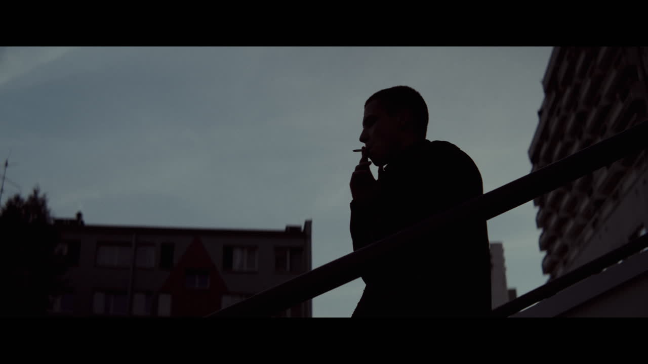 Silhouette of a Person Smoking in Urban Setting at Dusk