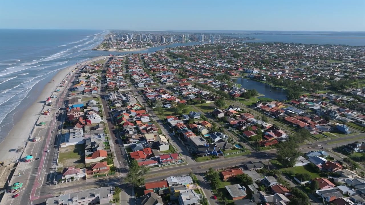 Cảnh quay lia ngang từ trên không một khu dân cư với những ngôi nhà đầy màu sắc ở Imbe, Brazil, hé lộ đường bờ biển, đầm phá và đại dương.