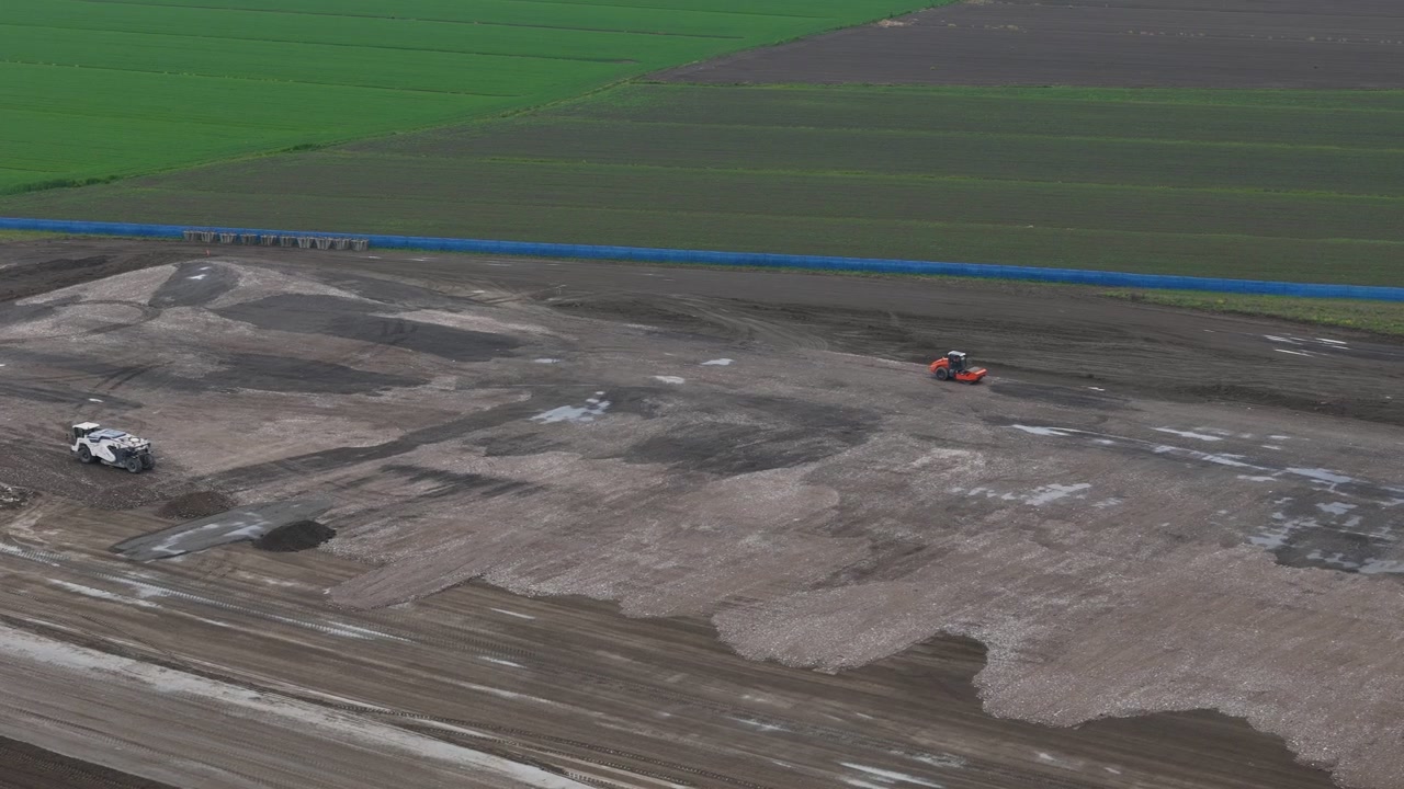 Movimento terra per un nuovo sviluppo industriale in Emilia-Romagna, Italia, che rivela la livellazione del sito, la stabilizzazione del terreno, macchinari pesanti e piattaforme di costruzione preparate, sorvolo in avanti con drone