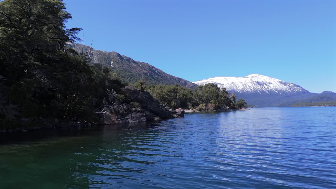 Drone fly close to Patagonian Lake landscape, water reflection below Mountains at Los Alerces National Park