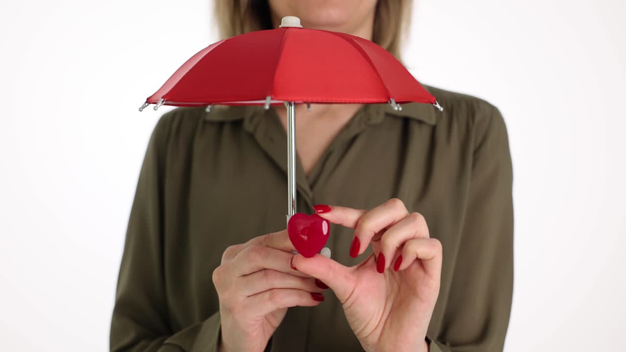 Donna copre un piccolo cuore con un ombrello rosso in uno studio luminoso