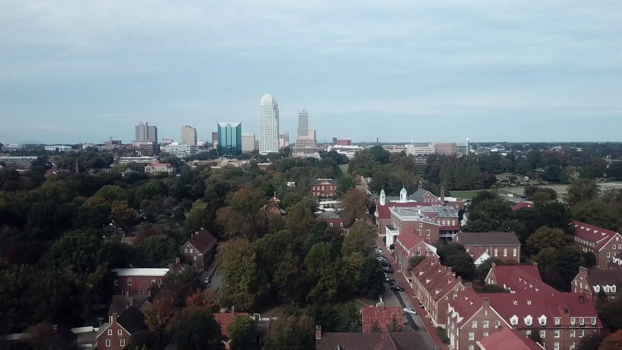 empuje aéreo old salem en primer plano con winston salem nc skyline en segundo plano.
