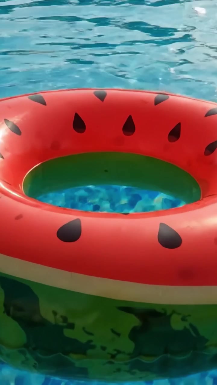 A Colorful Watermelon-Themed Float Ring Surrounded by Refreshing Blue Water in a Sparkling Swimming Pool during a Sunny Day