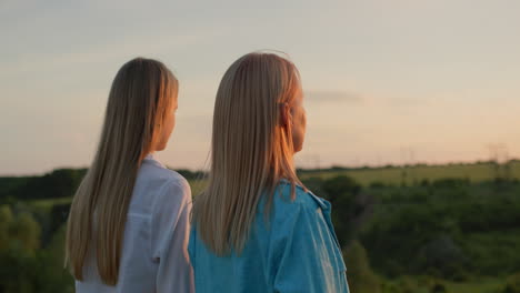 A-woman-with-her-teenage-daughter-admire-the-sunset-in-a-picturesque-valley