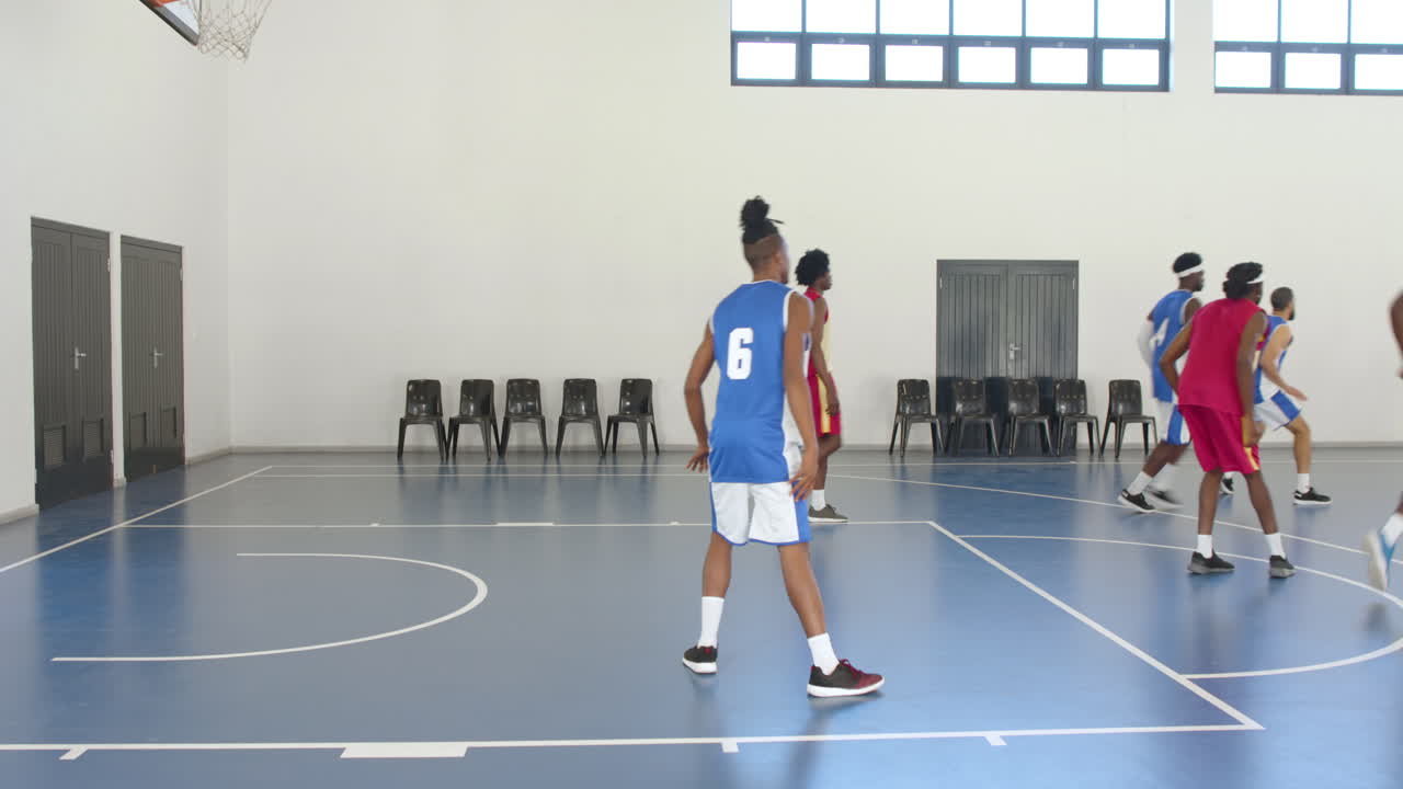 Multiracial male basketball players playing basketball, passing and throwing basketball in gym