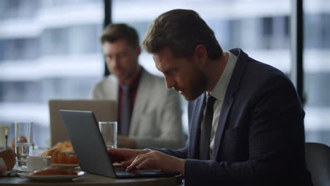 Trabajador-Independiente-Enfocado-Escribiendo-Teclado-De-Computadora-Portátil-En-Una-Cafetería-De-Coworking.