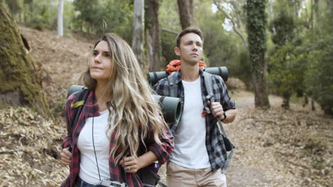 casal de mochileiros andando no caminho da floresta