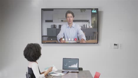 mujer de negocios afroamericana en videollamada con un colega caucásico en la pantalla