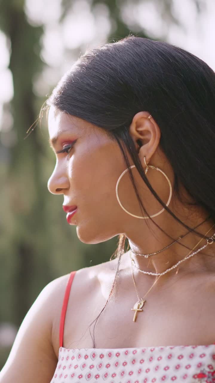 Close-up profile of a woman with dark hair and jewelry outdoors