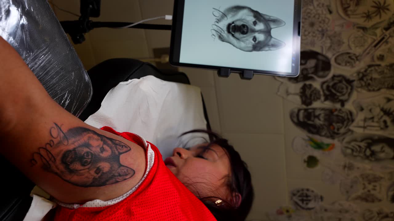 Happy woman lying on a stretcher while talks about her satisfying experience being tattooed her dog's face. Vertical