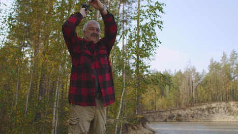 spin fishing in freshwater man is casting rod with bait in river standing on coast spending time at nature at weekend and holidays