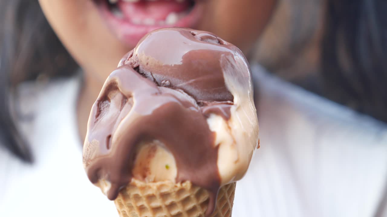 primer plano de una niña disfrutando de un cono de helado de chocolate y vainilla