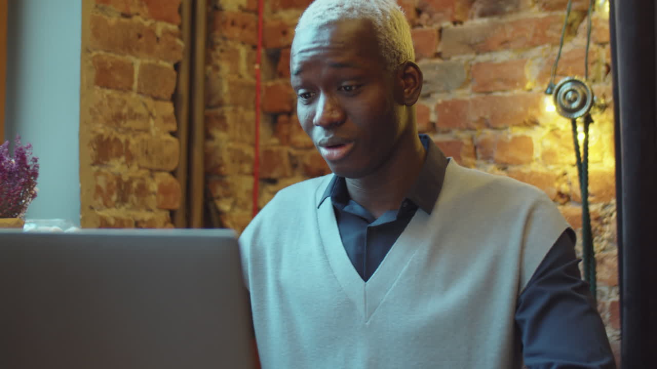 Black Man Talking via Video Call on Laptop in Cafe