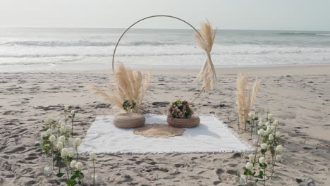 boho style wedding altar setup on beach with pampas grass circle and white rose path