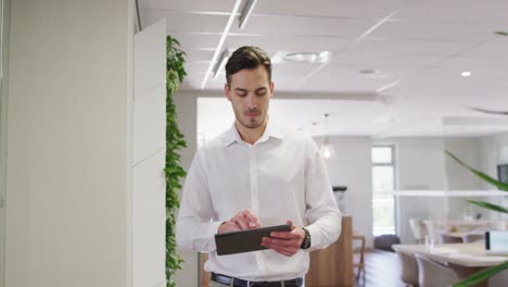 Caucasian-businessman-walking-using-tablet-at-office,-slow-motion