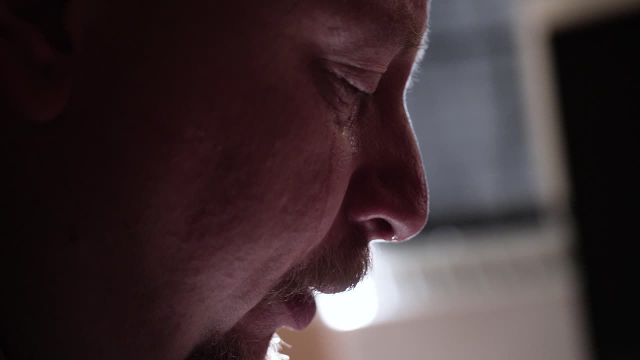Homem em luto olhando fotos no celular, chorando com lágrimas nos olhos