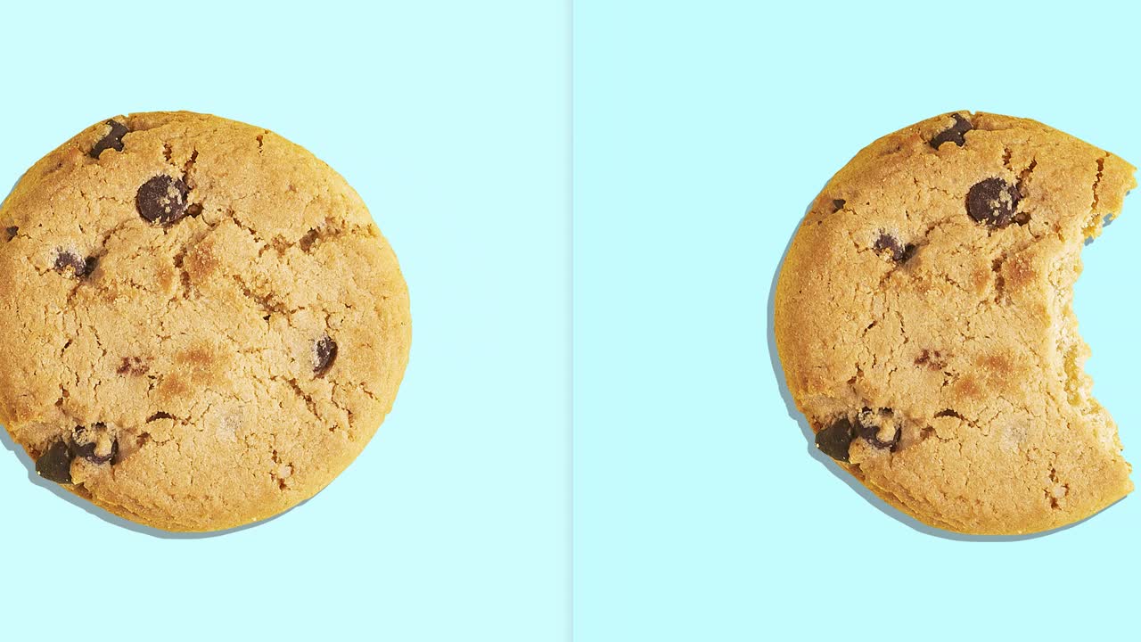 4k video of a whole and bitten American cookie with chocolate chunks moving from left to right against a blue background