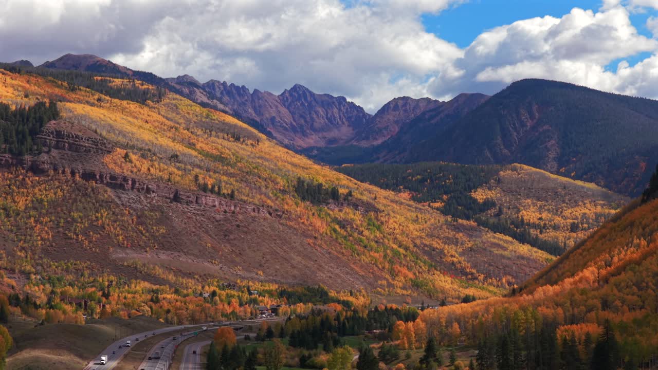Vail Pass cars traffic i70 interstate highway Vail Colorado fall autumn season Rocky Mountains Gore Range drone aerial colorful quaking aspen trees leaf peeping morning blue skies clouds upwards