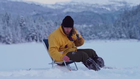 Man-Ice-Fishing-On-A-Frozen-Lake-In-Indre-Fosen,-Norway---wide