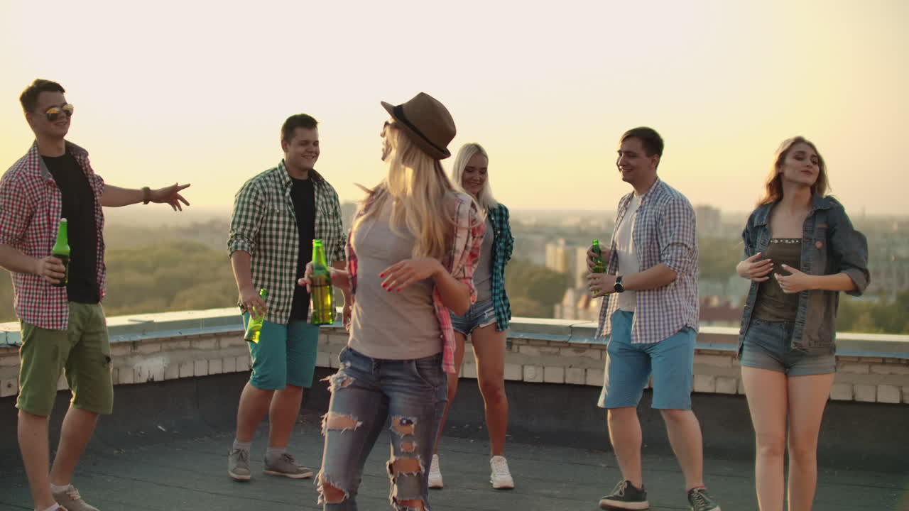 The russian blonde is dansing on the roof with her five friends. She enjoys this time with beer and good mood. She is wearing in fashionable hat ripped jeans white shirt and red plaid T-shirt.