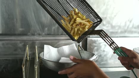 faceless cook putting french fries from basket in bowl