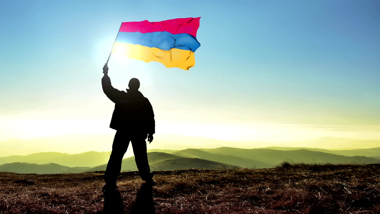 hombre ganador de silueta exitosa agitando la bandera armenia en la cima del pico de la montaña. fondo de bucle de cinemagraph